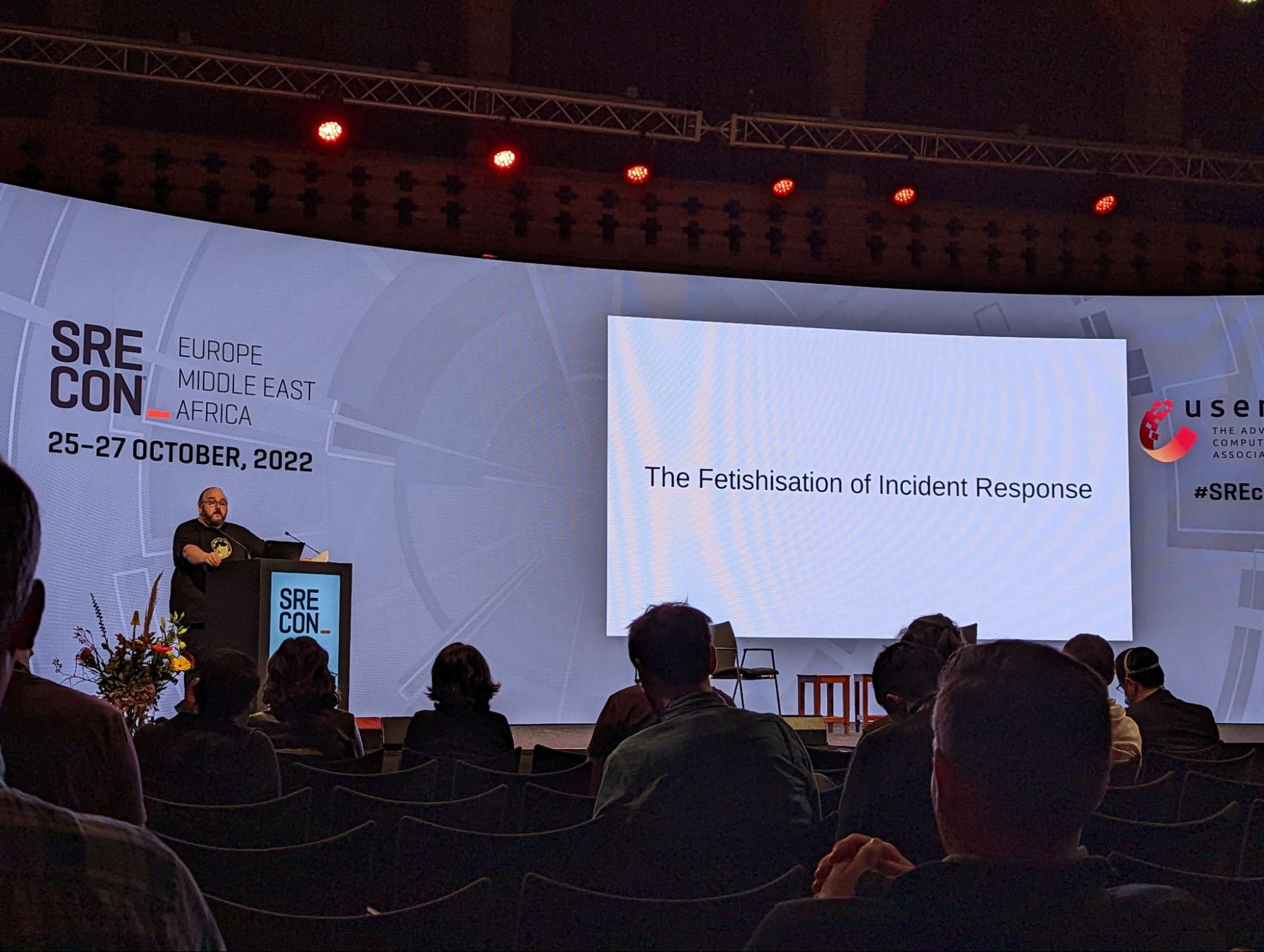 doc standing on stage with a slide saying “the Fetishisation of incident response”